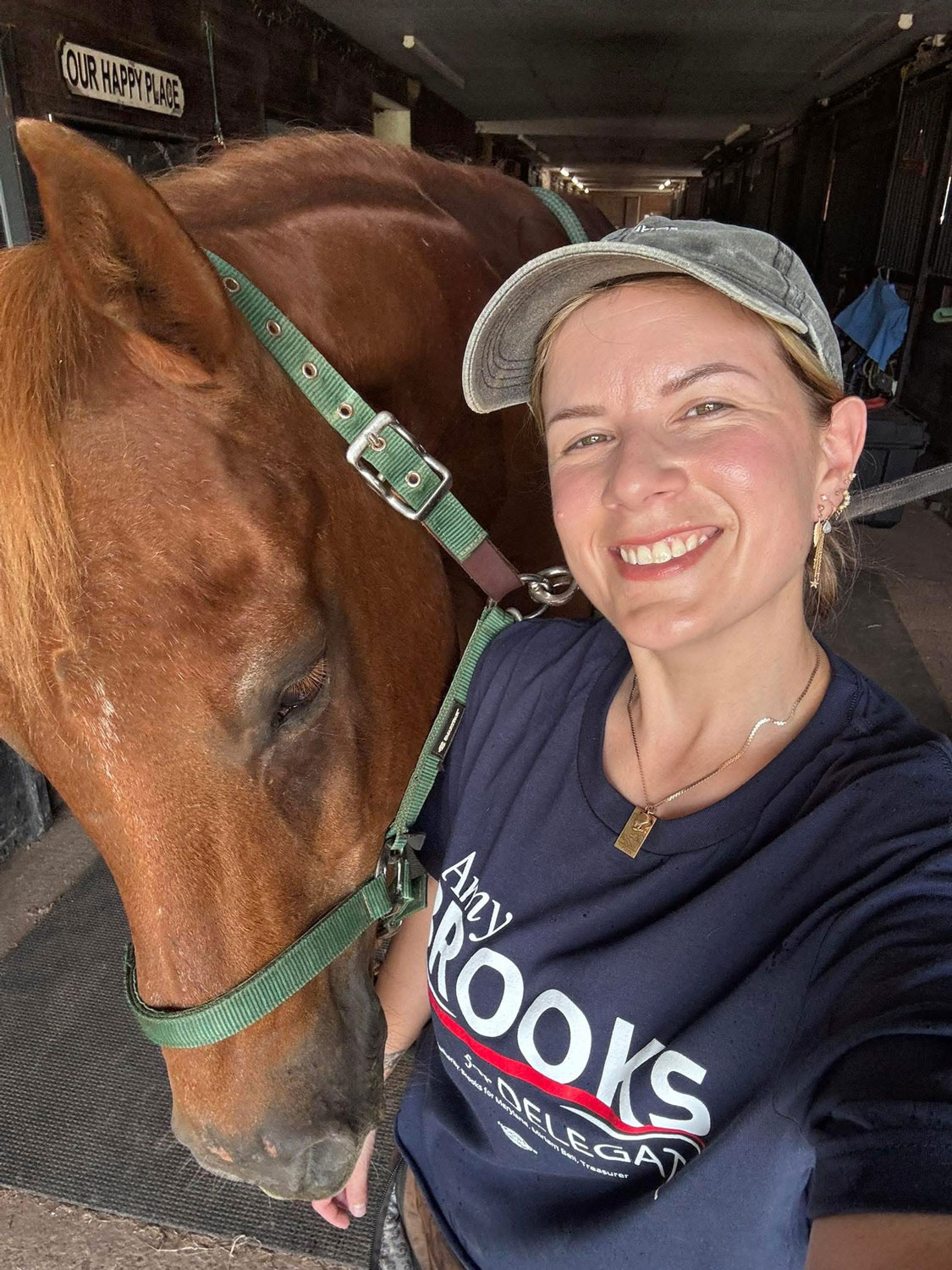 A supporter wearing a "Amy Brooks for Delegate" shirt smiling next to her horse