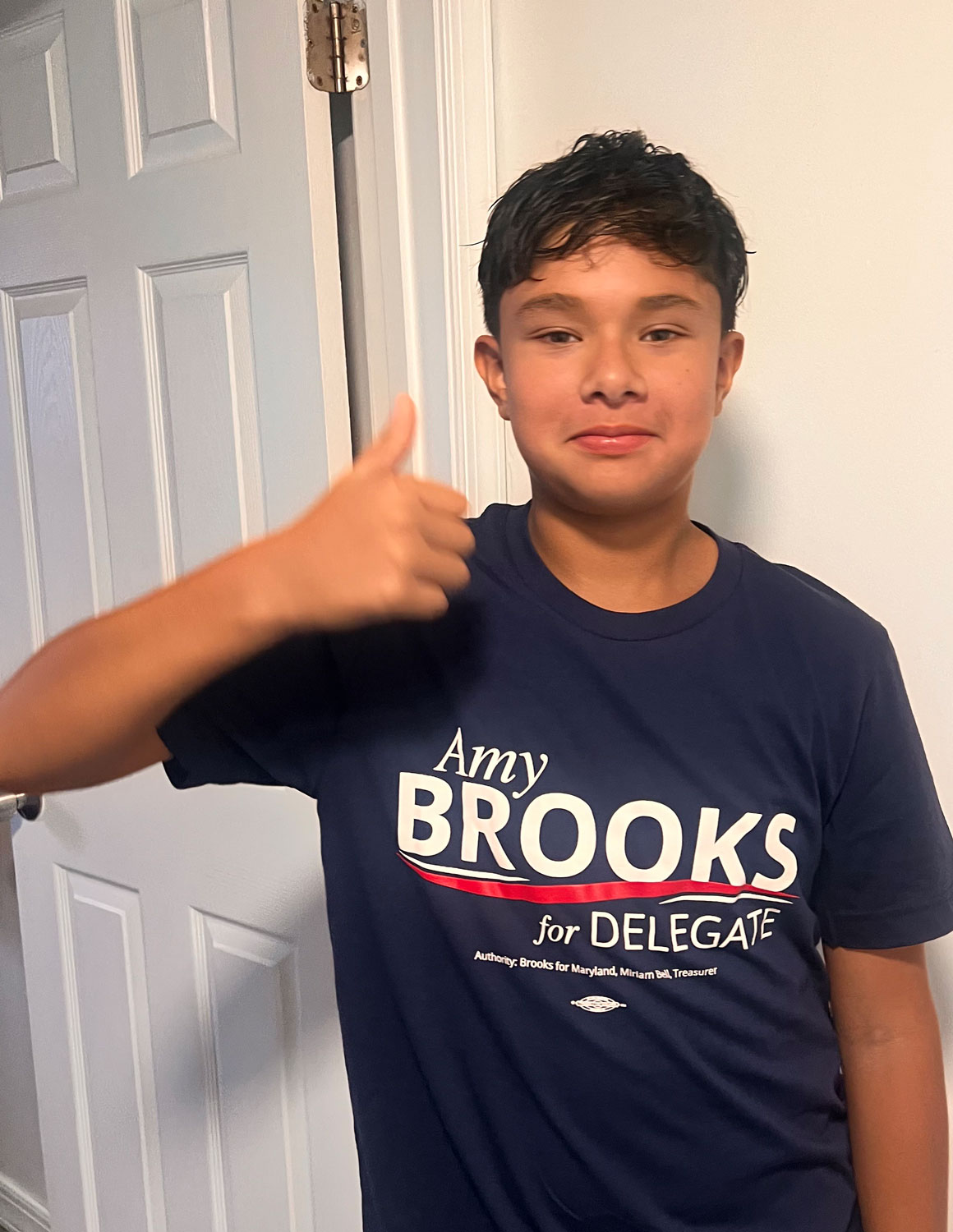 A student holding a thumbs up wearing a "Amy Brooks for Delegate" shirt